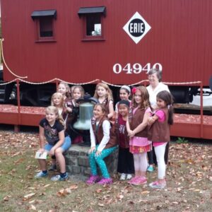 Museum Docent with brownie troop in front of Erie Caboose 